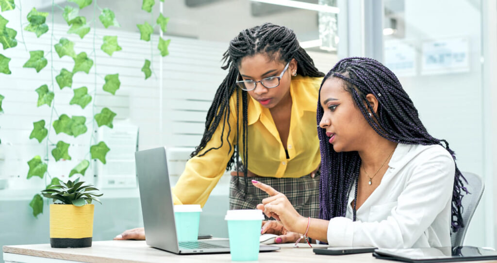 Two people working while looking at a laptop screen