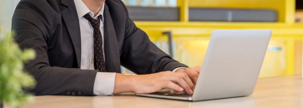 A girl staring at a laptop with a pencil in one hand and a notepad in the other